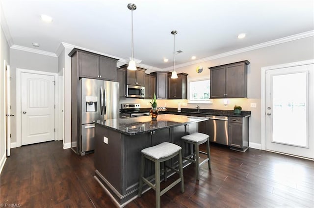 kitchen featuring dark brown cabinets, a breakfast bar area, a center island, dark stone counters, and stainless steel appliances