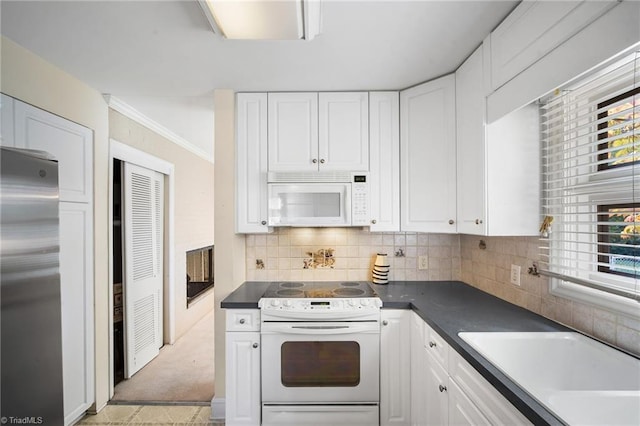 kitchen with sink, backsplash, white cabinets, crown molding, and white appliances