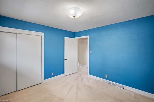 unfurnished bedroom featuring light carpet and a closet