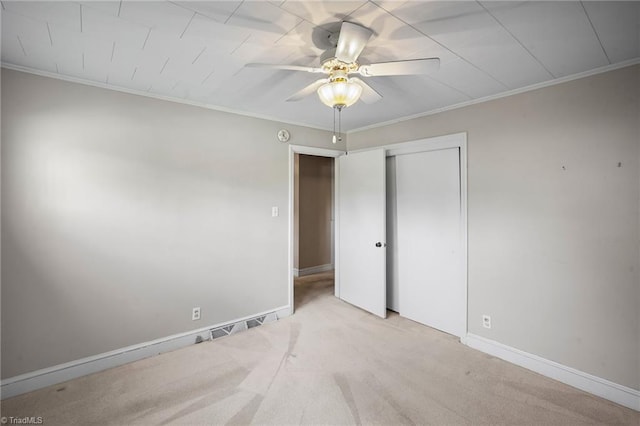 unfurnished bedroom with ornamental molding, light colored carpet, ceiling fan, and a closet