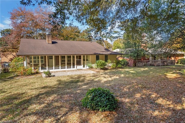 back of property with a yard and a sunroom