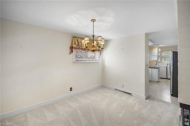 unfurnished dining area with washing machine and clothes dryer, a chandelier, and light carpet