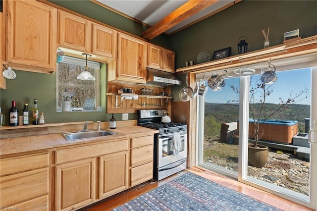 kitchen with light brown cabinetry, beam ceiling, a sink, light countertops, and stainless steel gas range oven