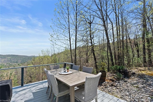 deck featuring outdoor dining area and a wooded view