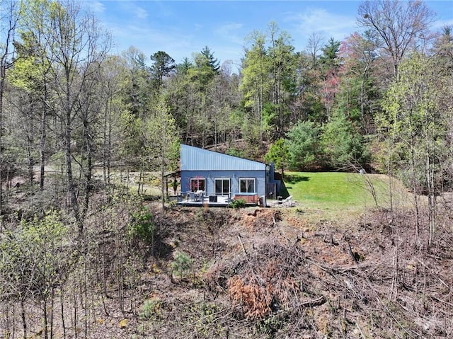 exterior space with a view of trees, a yard, and a deck