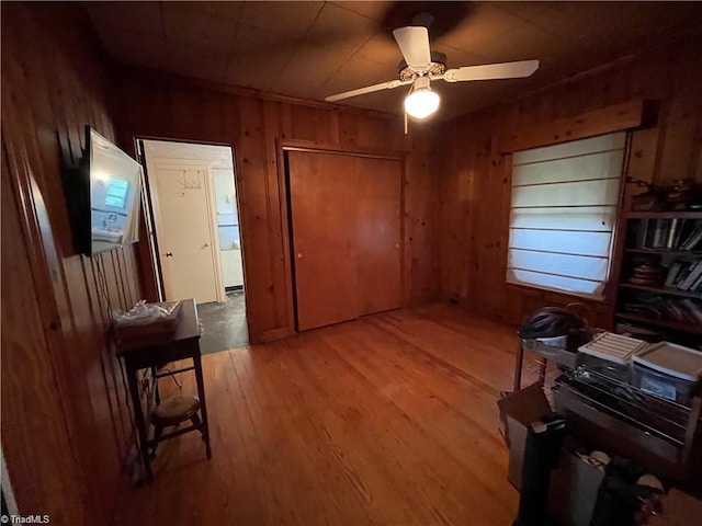 office featuring wood walls, hardwood / wood-style floors, and ceiling fan