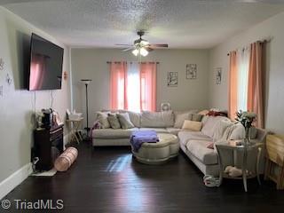 living room featuring ceiling fan, a textured ceiling, and dark hardwood / wood-style flooring