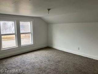 bonus room featuring lofted ceiling and dark colored carpet