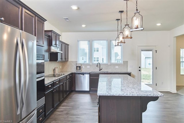 kitchen with a center island, sink, hanging light fixtures, stainless steel appliances, and backsplash