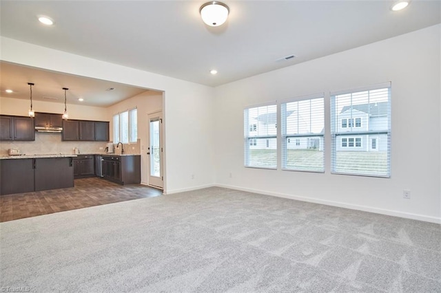 unfurnished living room with dark carpet, a wealth of natural light, and sink