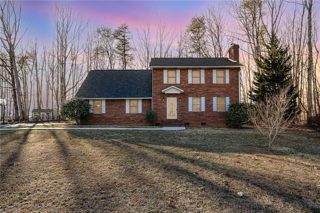 view of front facade featuring crawl space, brick siding, a chimney, and a front lawn