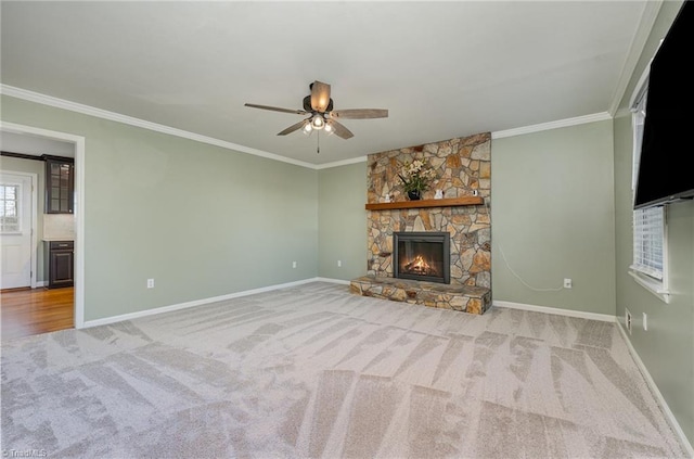 unfurnished living room featuring crown molding, a stone fireplace, baseboards, and light colored carpet