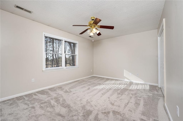 empty room featuring visible vents, light carpet, baseboards, and a textured ceiling