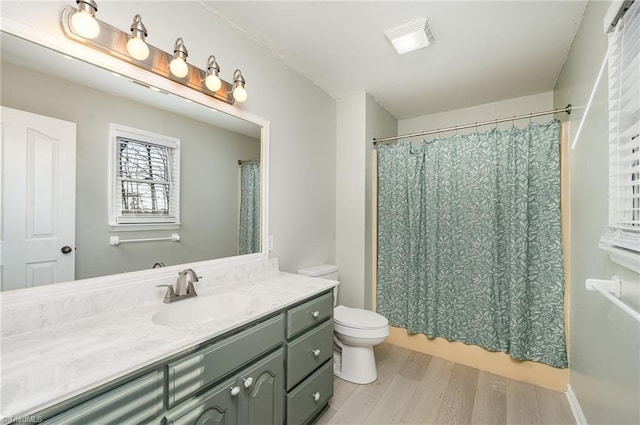 full bath with visible vents, toilet, vanity, wood finished floors, and a shower with curtain