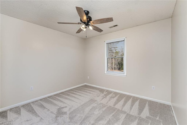 carpeted empty room featuring a ceiling fan, visible vents, baseboards, and a textured ceiling