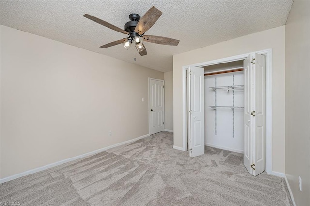 unfurnished bedroom featuring a textured ceiling, baseboards, a closet, and light colored carpet