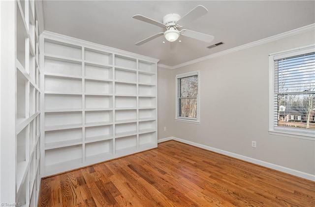 spare room featuring visible vents, ornamental molding, ceiling fan, wood finished floors, and baseboards