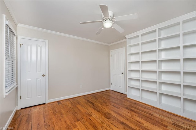 unfurnished bedroom with a ceiling fan, crown molding, baseboards, and wood finished floors