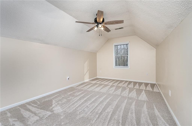 additional living space featuring lofted ceiling, light colored carpet, visible vents, a textured ceiling, and baseboards