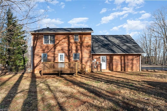 back of property featuring a deck, a yard, and brick siding