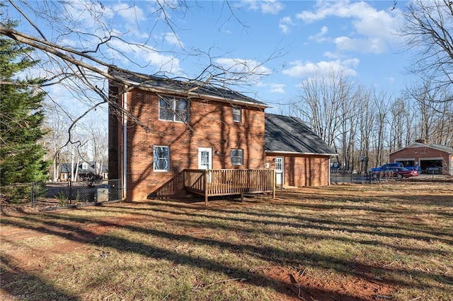 rear view of property featuring a yard, brick siding, fence, and a wooden deck