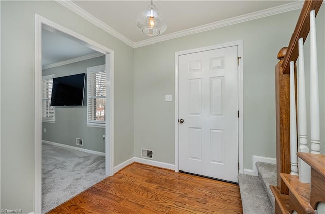 entrance foyer with ornamental molding, light wood-style flooring, visible vents, and baseboards