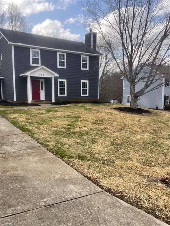 colonial home with a chimney and a front yard