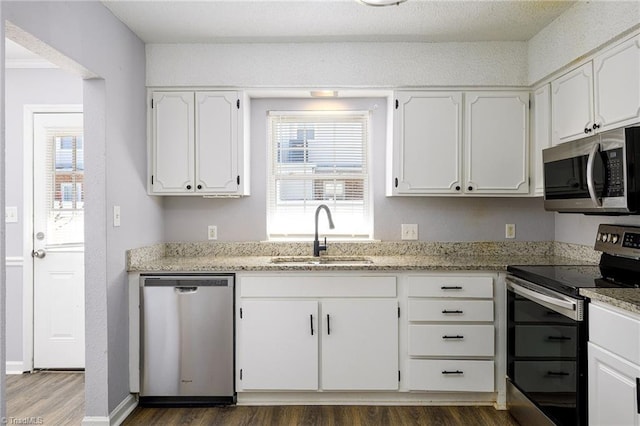 kitchen with light stone counters, dark wood finished floors, appliances with stainless steel finishes, white cabinetry, and a sink