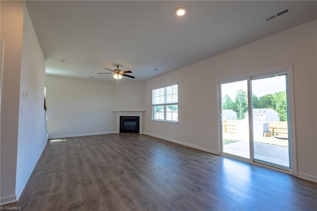 unfurnished living room featuring dark wood-type flooring, a ceiling fan, baseboards, a glass covered fireplace, and recessed lighting