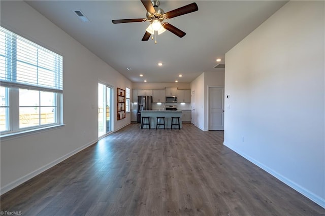 unfurnished living room featuring dark wood-type flooring, a ceiling fan, baseboards, and recessed lighting