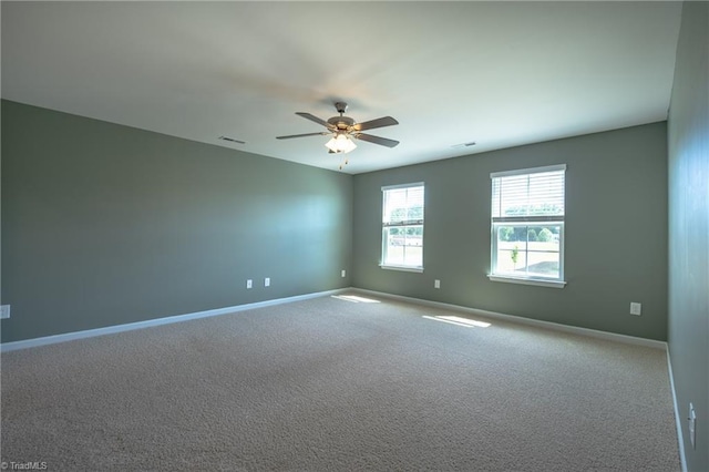 carpeted spare room with baseboards and a ceiling fan