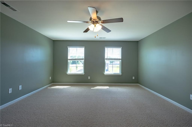 carpeted empty room featuring ceiling fan and baseboards