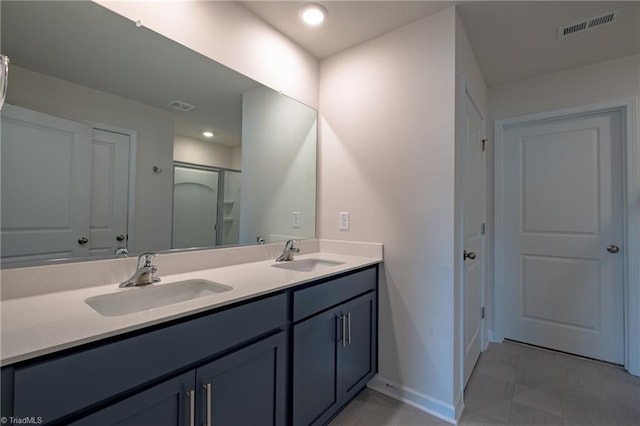 bathroom featuring baseboards, double vanity, and a shower with shower door