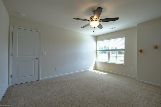 carpeted spare room featuring baseboards, ceiling fan, and a smoke detector