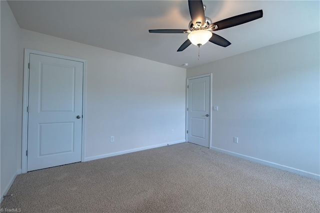 carpeted empty room with baseboards and a ceiling fan