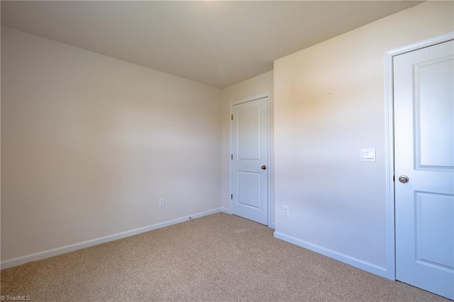 unfurnished bedroom featuring light carpet and baseboards