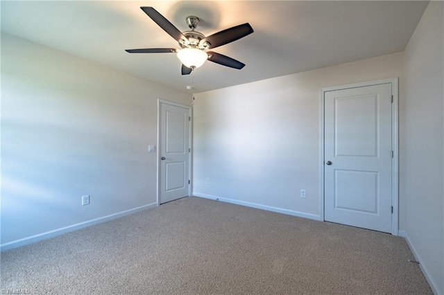spare room featuring carpet floors, a ceiling fan, and baseboards