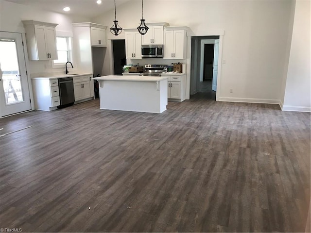 kitchen featuring appliances with stainless steel finishes, pendant lighting, dark hardwood / wood-style flooring, and white cabinetry