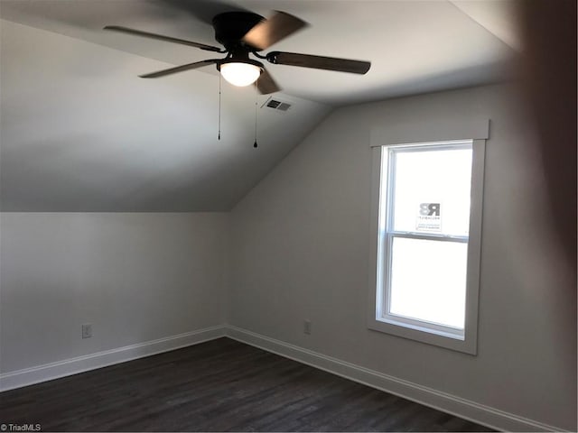 bonus room with vaulted ceiling, ceiling fan, a wealth of natural light, and dark wood-type flooring