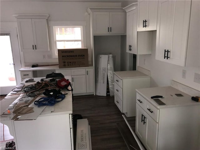 kitchen with white cabinets, a center island, and dark wood-type flooring