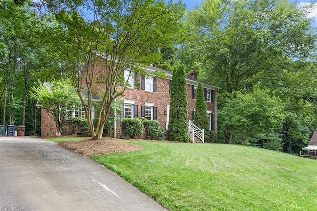 3717 Rock Haven Dr, Greensboro, NC 27410 - colonial-style house featuring a front lawn, a chimney, brick siding, and driveway