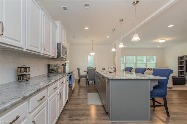 5968 Crescentbrook Ln, Clemmons, NC 27012 - kitchen with appliances with stainless steel finishes, a kitchen bar, decorative backsplash, white cabinets, and wood finished floors