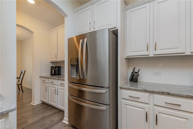 5968 Crescentbrook Ln, Clemmons, NC 27012 - kitchen featuring stainless steel refrigerator with ice dispenser, arched walkways, white cabinetry, tasteful backsplash, and wood finished floors
