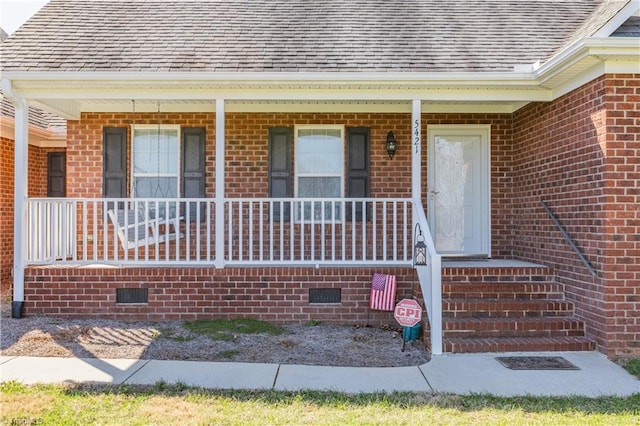 doorway to property with crawl space, brick siding, and roof with shingles