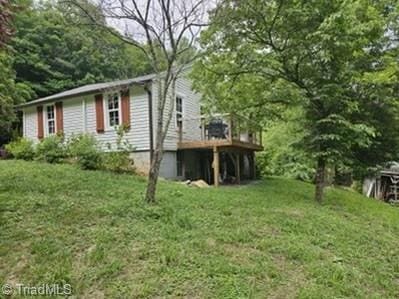 view of side of property featuring a wooden deck and a lawn