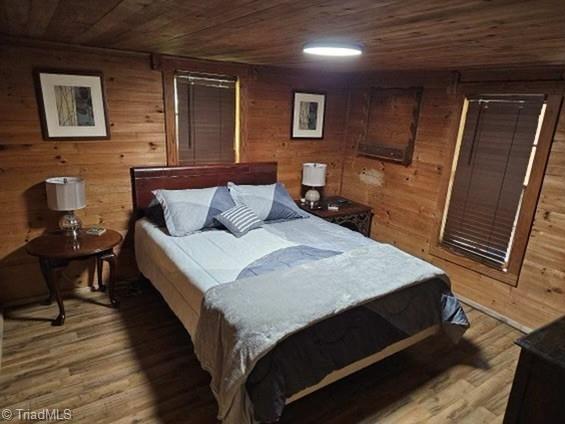 bedroom featuring wood-type flooring, wooden walls, and wood ceiling