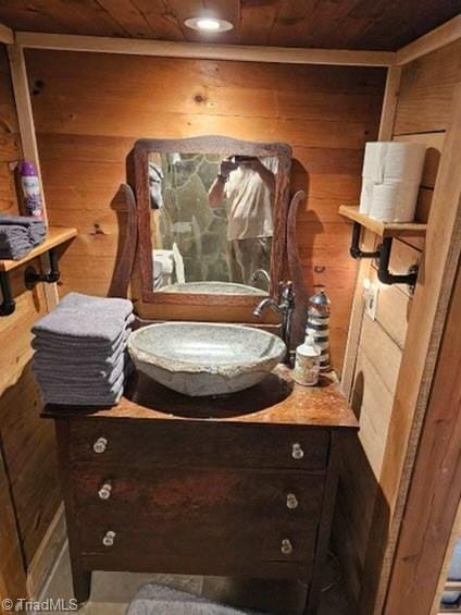 bathroom featuring vanity, wooden walls, and wooden ceiling