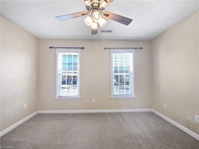 carpeted empty room featuring visible vents, a textured ceiling, baseboards, and a ceiling fan