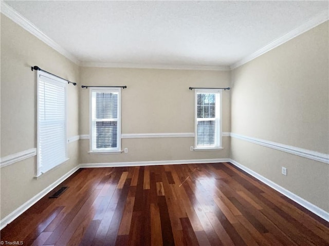 spare room featuring hardwood / wood-style flooring, crown molding, baseboards, and visible vents