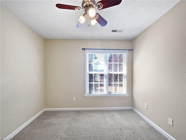 empty room featuring visible vents, a textured ceiling, carpet floors, baseboards, and ceiling fan